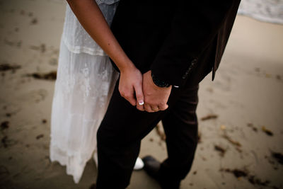 Midsection of couple standing on beach