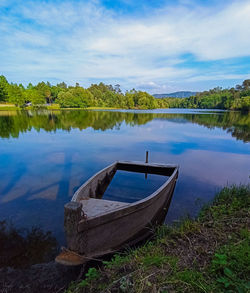 Boat moored on lake against sky