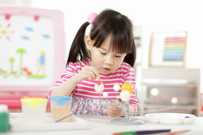 Girl looking away while sitting on table