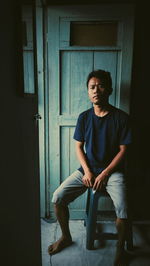 Full length of young man sitting at entrance of building