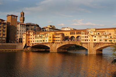 Bridge over river in city against sky