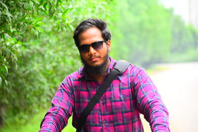 Portrait of young man wearing sunglasses while standing against plants