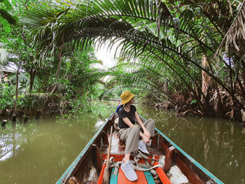 People on boat in river against trees