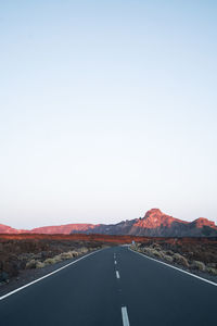 Road by mountains against clear sky