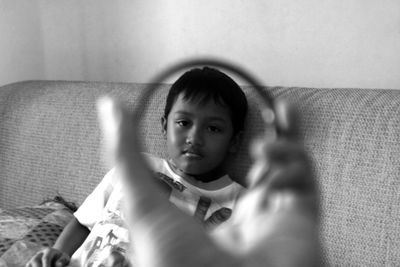 Portrait of boy sitting on sofa seen through bangle at home