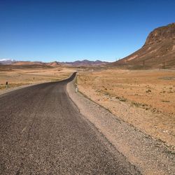 Country road against clear blue sky