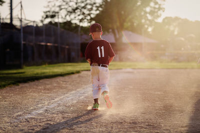 Rear view of boy walking on baseball field