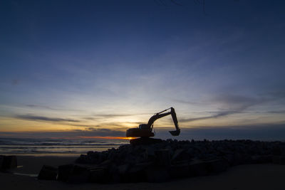 Silhouette rocks on beach against sky during sunset