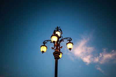 Low angle view of illuminated street light against blue sky