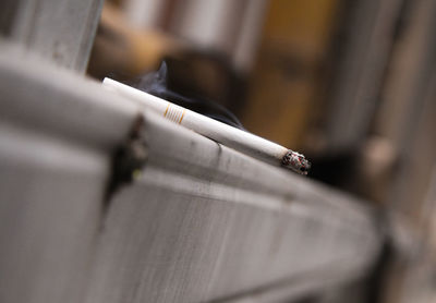 Close-up of cigarette on railing