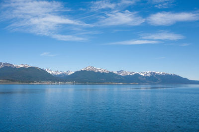 Scenic view of lake by mountains against blue sky