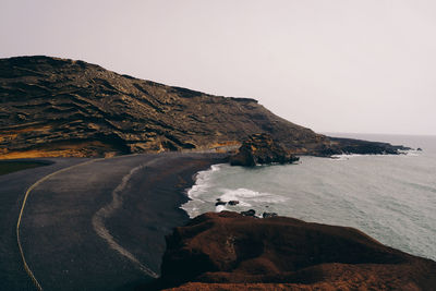 Scenic view of sea by cliff against clear sky