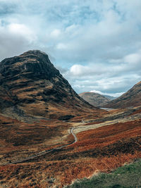 Scenic view of road by mountains against sky