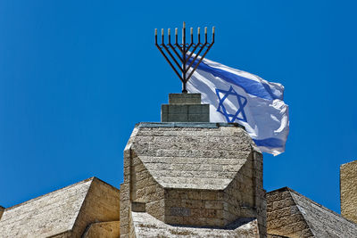 Low angle view of israeli flag waving on historic building against clear blue sky