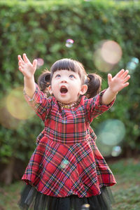 Cute girl playing with bubbles against plants