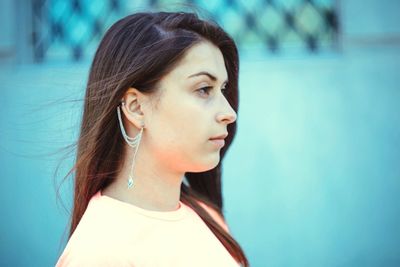 Side view of young woman wearing earring looking away outdoors