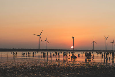 Silhouette of people on beach at sunset