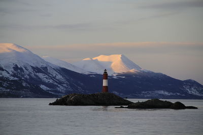 Scenic view of sea by mountain against sky during sunset