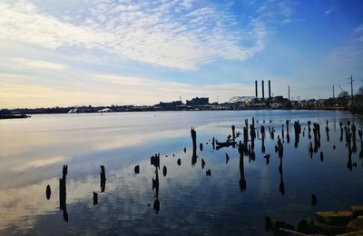 Wooden posts in sea against sky