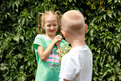 Boy gives a bouquet of daisies to the girl with joy, blonde, valentines or mother day concept.