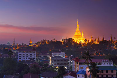 Illuminated buildings against sky during sunset