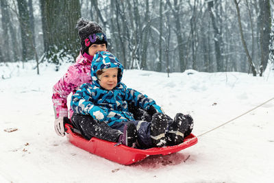 Cute kids sitting on sledge during winter