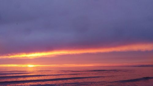 Scenic view of sea against dramatic sky during sunset