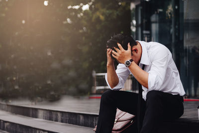 Businessman with head in hands sitting on steps