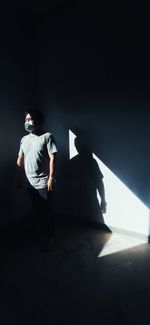 Rear view of man standing against wall in darkroom