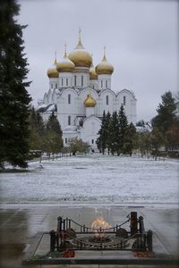 Church by building against sky during winter