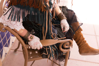 Low section of woman wearing costume sitting on chair