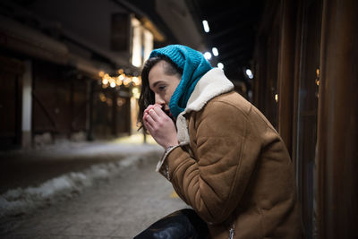 Side view of man on snow covered street at night