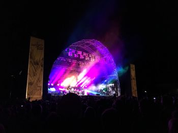 Crowd at music concert against sky at night