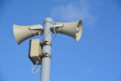 Low angle view of loud speakers against blue sky