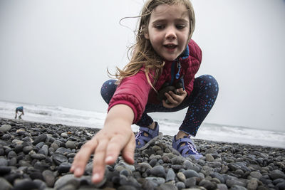 Full length of girl with pebbles on beach