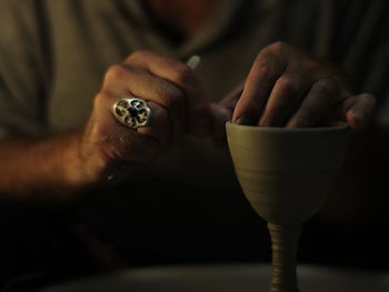 Midsection of man making clay container in workshop