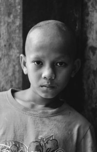 Close-up portrait of serious bald boy outdoors