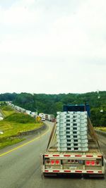 Vehicles on road against sky in city