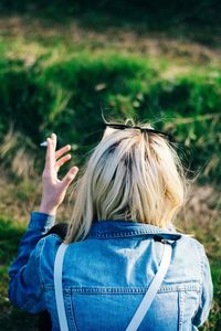 Rear view of woman with arms raised on field