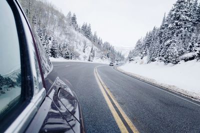 Road amidst trees against sky during winter