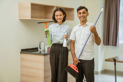 Portrait of woman holding shopping bags against wall at home