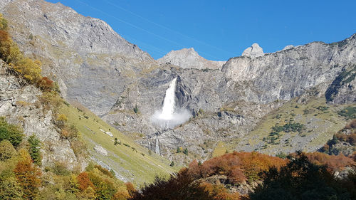 Scenic view of mountains against sky and waterfall