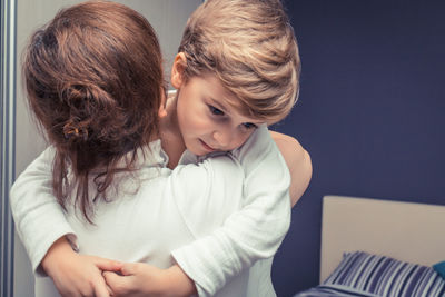 Rear view of grandmother carrying son in bedroom