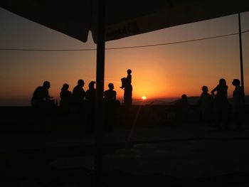 Silhouette people at beach against sky during sunset