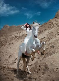 Full length of woman riding horse on mountain