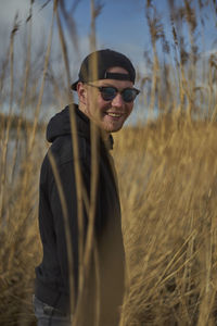 Portrait of young man wearing sunglasses standing on field