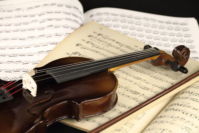 High angle view of violin on sheet music against black background