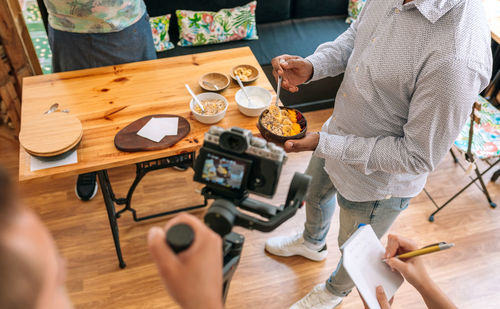 Cropped hand of people recording food at restaurant