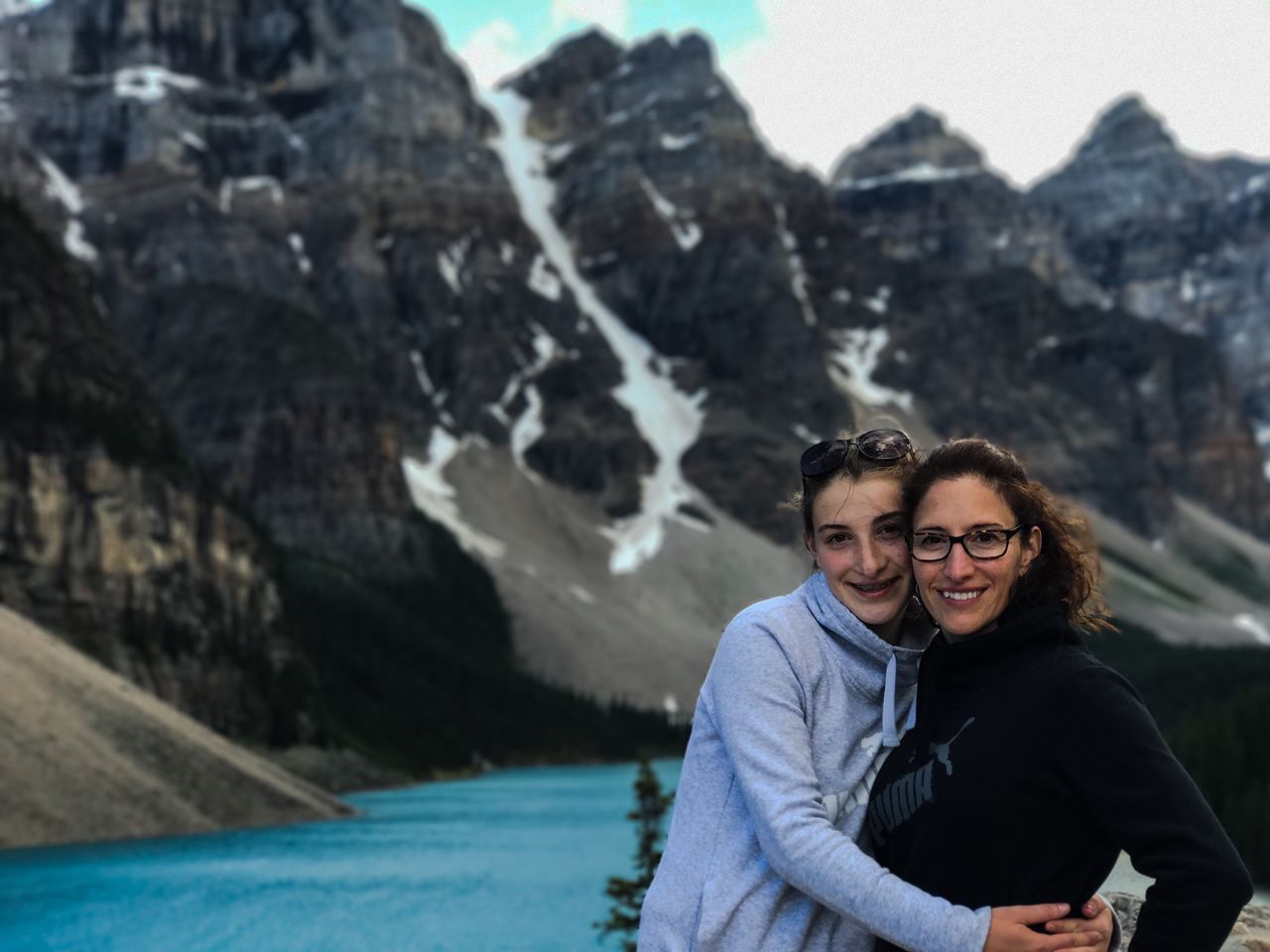 real people, two people, looking at camera, mountain, water, smiling, togetherness, leisure activity, happiness, portrait, young women, lifestyles, nature, day, focus on foreground, young adult, love, outdoors, standing, beauty in nature, bonding