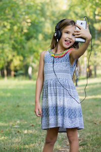 Cute girl wearing headphones doing selfie at park